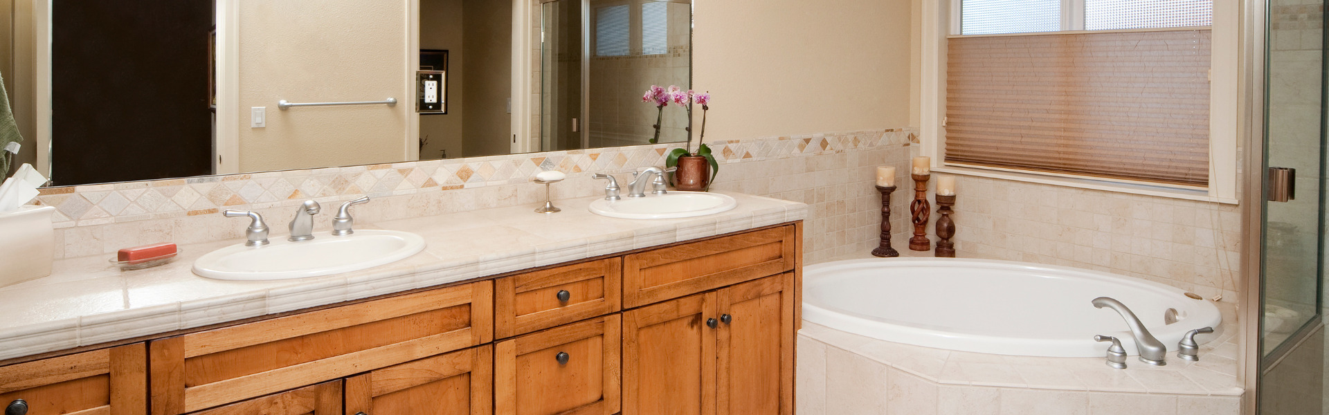Double vanity and freestanding bath in a renovated bathroom with mosaic tile splashback