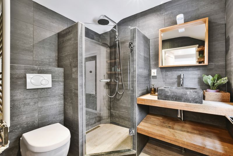 Modern bathroom design with dark tiling, timber vanity and glass shower