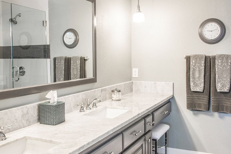 Renovated bathroom with marble-look double vanity and walk-in glass shower