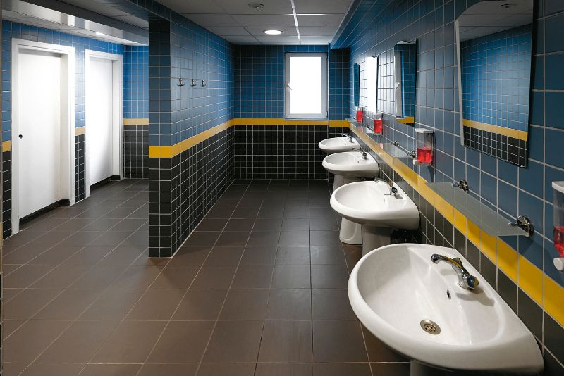 Commercial bathroom with blue tiling and a row of basins