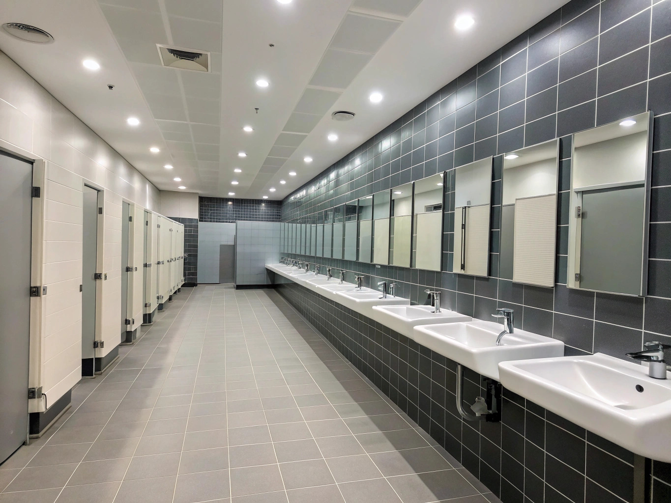 Completed commercial bathroom fitout with a row of basins and cubicles